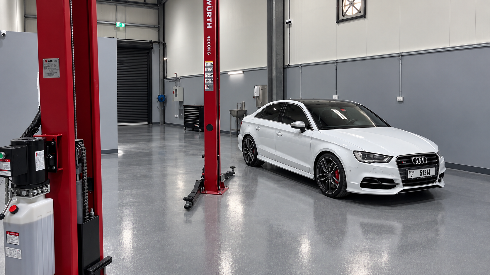 White Audi S3 beside red vehicle lifts at Wolfsburg Motor Service in Dubai