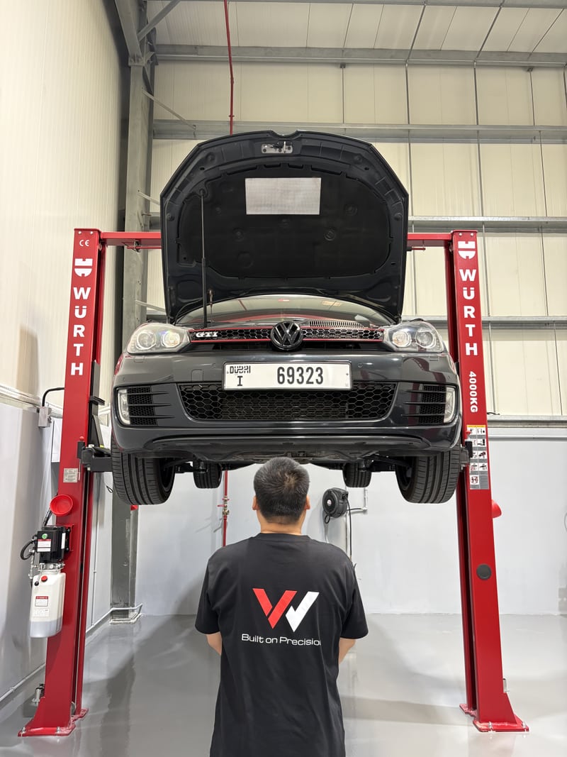 Wolfsburg technician working below the Mk6 GTI on a vehicle lift