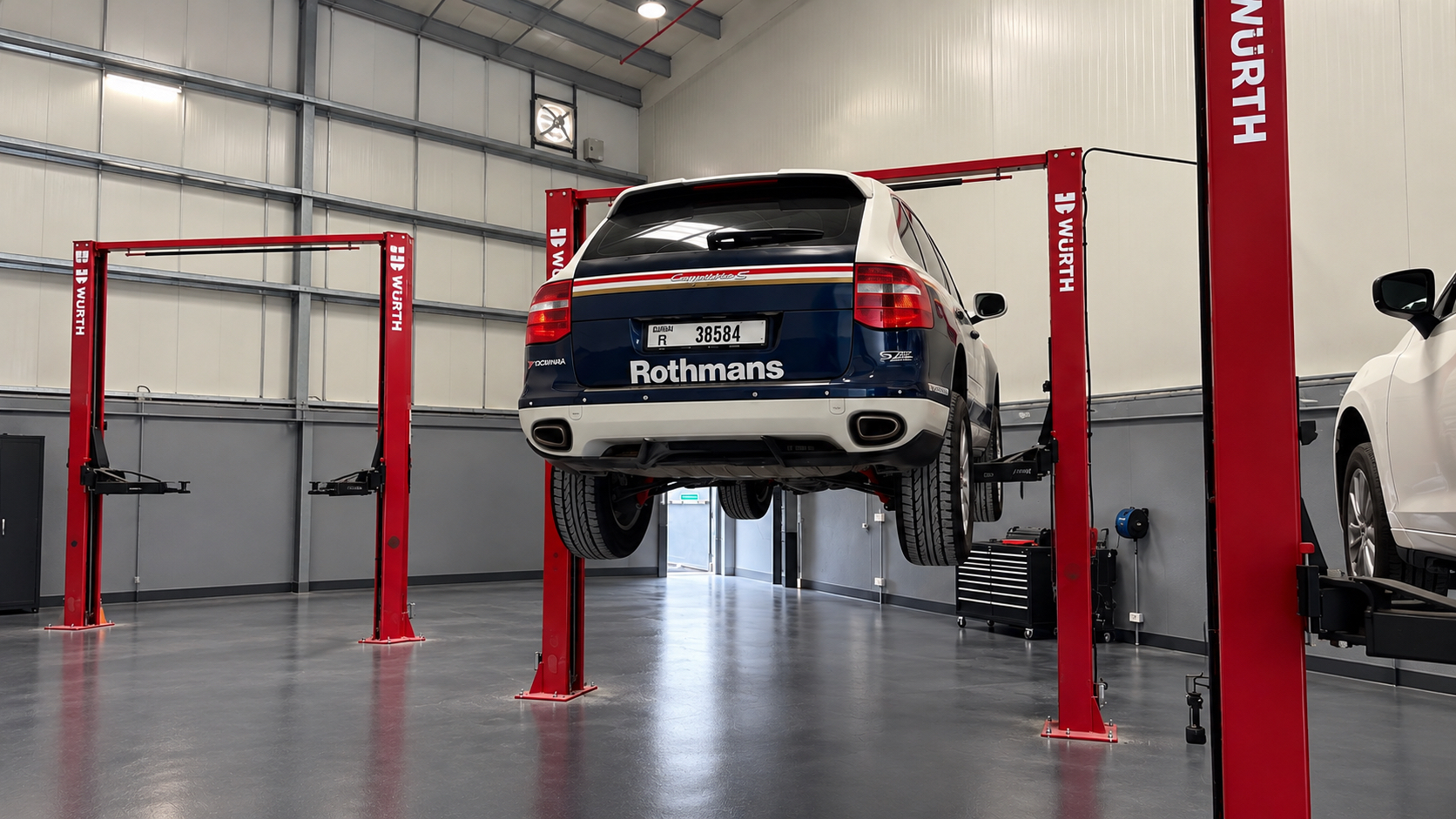 Porsche Cayenne raised on a red workshop lift